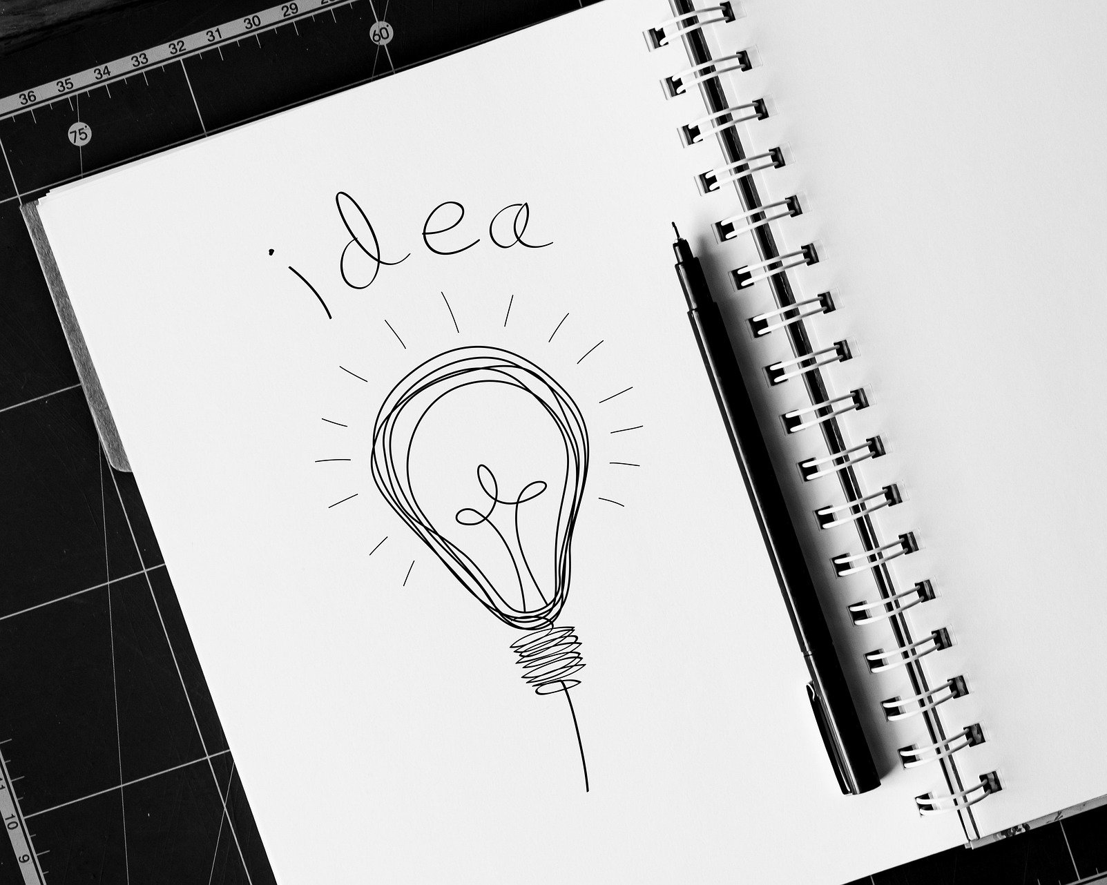Ein aufgeschlagenes Skizzenbuch mit einer Zeichnung einer Glühbirne und der Überschrift "idea"