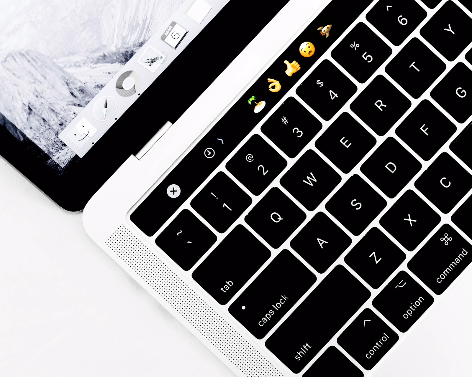 Schwarz-Weiß-Nahaufnahme eines MacBooks mit farbigen Emojis